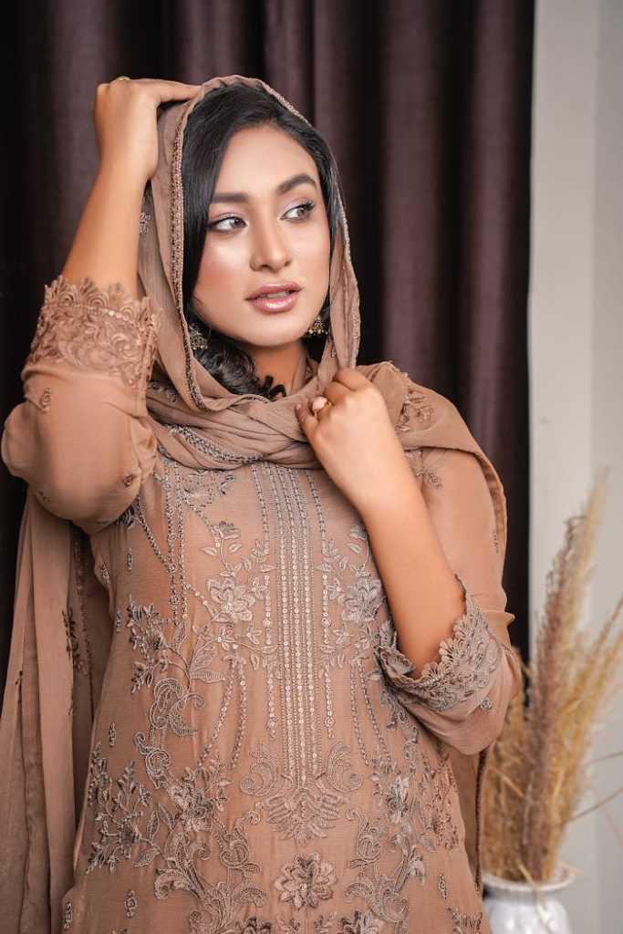 Woman in an intricately embroidered dress and headscarf, exuding elegance and grace.