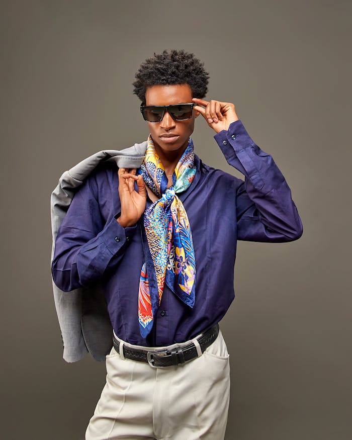 Fashionable young man wearing vibrant scarf and sunglasses striking a confident pose.
